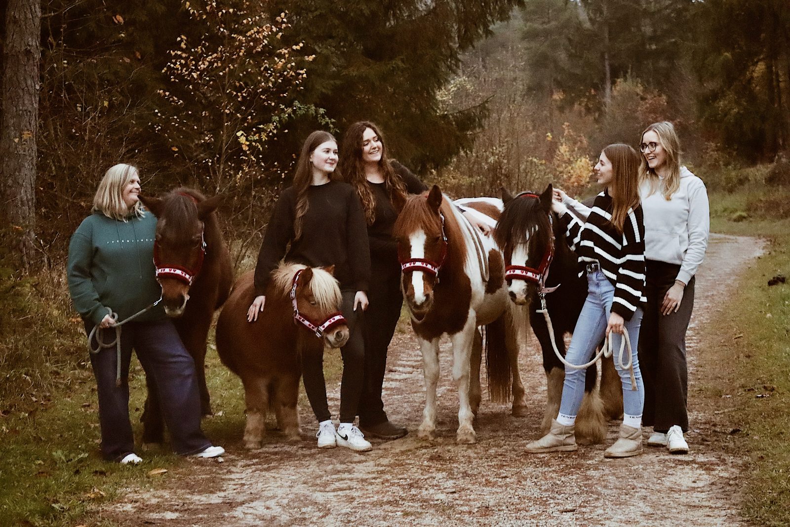 Gruppe von Kindern und Jugendlichen mit ihren Ponys auf dem Weg am Waldrand